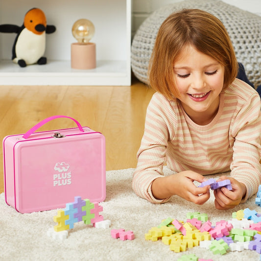 Girl playing with pastel BIG pieces next to a pink BIG Metal Suitcase - 70 pc