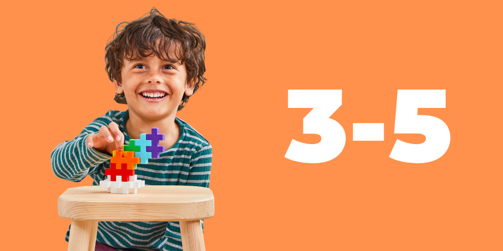 Ages 3-5: smiling boy building with BIG Plus-Plus pieces on an orange background