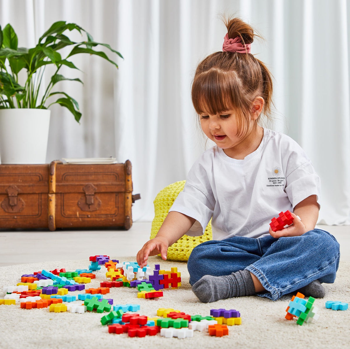 Girl sitting on the floor building with colorful BIG Plus-Plus pieces