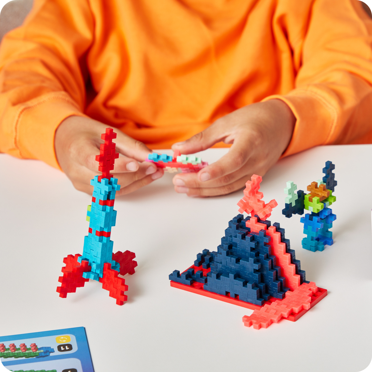 Built with just one shape: child building a Plus-Plus rocket and pyramid