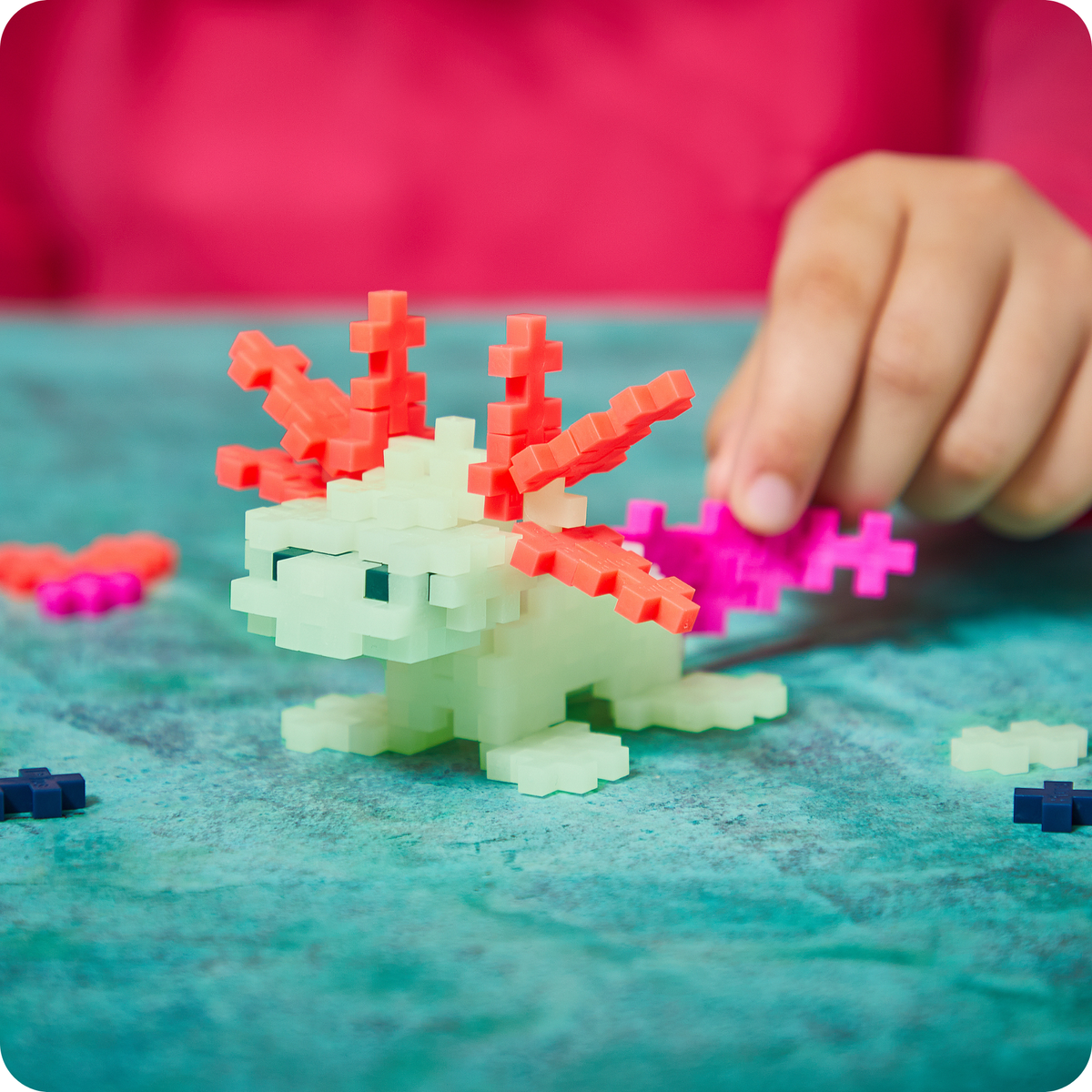 Built with just one shape: child building a glowing Plus-Plus axolotl