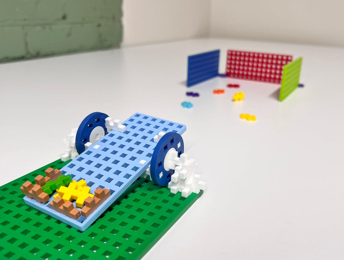 Plus-Plus vehicle with blue wheels on a green baseplate ramp