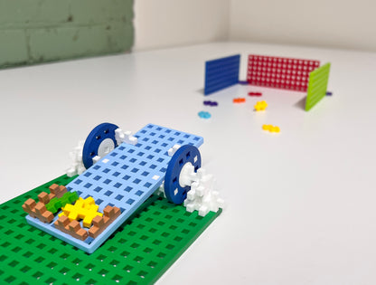 Plus-Plus vehicle with blue wheels on a green baseplate ramp
