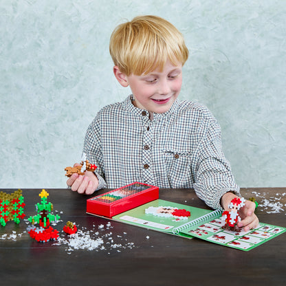 Smiling boy building a Santa from a Holiday Activity Pad with tree and reindeer builds