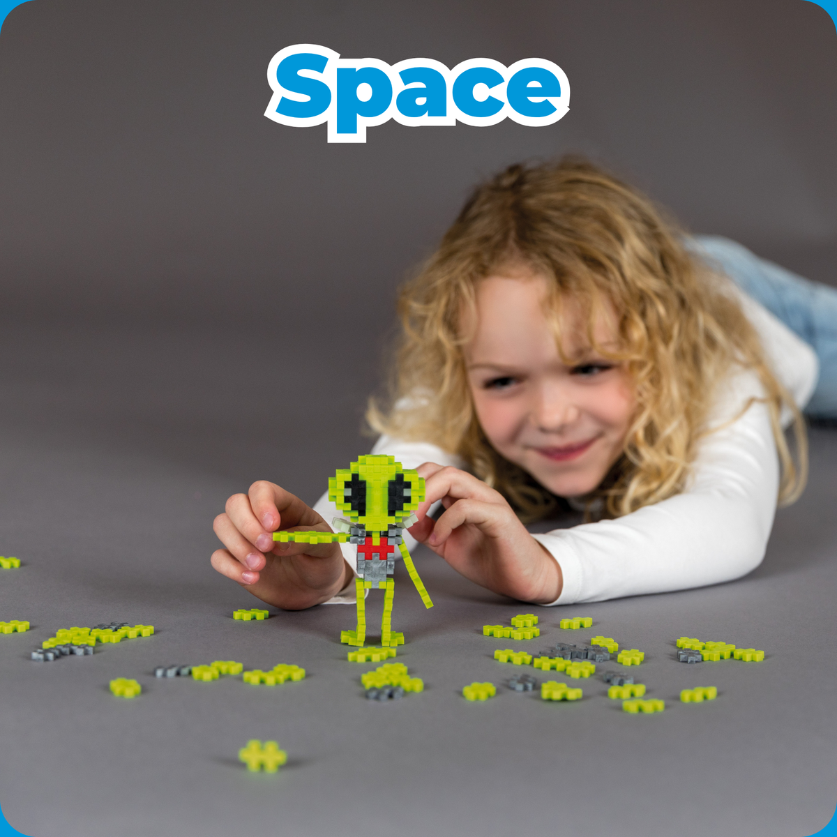 Shop by Theme - Space: smiling girl playing with a green Plus-Plus alien build